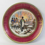 Belo e antigo prato de coleção, em porcelana europeia, Napoleônica, tendo ao centro em policromia, representando "Incendic de Moscou". Abas na cor grená, com pinturas diversas em dourado. Perdas no dourado. Diam. 24,5 cm.