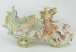 Floreira em biscuit europeu policromado, na forma de trenó puxado por animal alado, e adornada com figura feminina e querubim. Med. 14x26x8,5cm.
