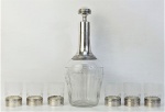 Conjunto de licoreiro e 6 copinhos em cristal e prata francesa, com contraste de teor 950 milésimos. Cristal com lapidações de olivas, sulcos, frisos e folhas em satiné. Prata do licoreiro com minúsculas mossas. Alts. licoreiro 26,5 cm. e Alt. copos 6 cm.