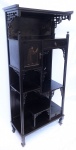 Antigo porta bibelô, oriental em madeira entalhado, decorado com trabalhos em relevo e apliques em madreperola. Porta e gaveta na parte superior e uma gavetinha na inferior. Oito platôs. Med. 147x68x31cm.