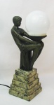 Luminária estilo Art-deco, em bronze representando "Figura feminina" sustentando globo, sendo este em material sintético. Base em degraus de mármore. Alt. total 35,5cm.
