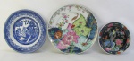 Três pratos decorativos em porcelana, sendo um português da manufatura Vista Alegre, com decoração folha de tabaco, outro com decoração pombinhos e o outro japonês, com pintura esmaltada de flores, frutas e pássaro. Diam. maior e menor 27,5 e 18,5cm.