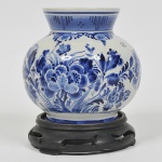 DELFT - Vaso bojudo em porcelana holandesa, com bojo gomado e decorado com flores e folhas em característico blue and white. Acompanha Peanha em madeira entalhada. Peça marcada na base. Med: 15cm
