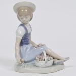 LLADRÓ - "Dama com cesto de flores" Escultura em porcelana espanhola esmaltada e vitrificada. Peça marcada e numerada na base. Med: 14 x 10 x 18cm