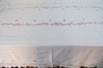Uma (1) toalha de mesa retangular, confeccionada em linho , com bordado floral vazado em linha branca, com pequenas manchas de guardado. Med. 270 x 160 cm.