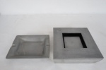 Dois (02) cinzeiros para charuto em duro alumínio liso e polido. Med. quadrado 5,5 x 19 x 19 cm. retangular 2,5 x 19 x 15 cm.