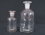 Dois antigos recipientes de farmácia em vidro translúcido. Med. maior 17,5 x 8 cm diâmetro, menor 12 x 5,5 cm diâmetro.