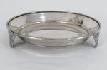 Uma (1) salva em metal espessurado a prata, em formato circular, apoiada sobre três pés cinzelados em volutas. Marcado Sta Rita.Med: 3 x 14,5 cm.