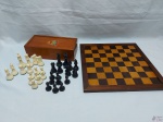 Tabuleiro de xadrez em madeira com peças em resina, possui um estojo em madeira para as peças. Medindo o tabuleiro 32,5cm x 32,5cm e o rei 7cm de altura.