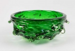 MURANO BULLICANTE   DESIGN FLAVIO POLO PARA  SEGUSO VETRI D'ARTE DE MEADOS DO SEC. XX .   GRANDE E BELO BOWL/CENTRO DE MESA EM VIDRO ARTÍSTICO DE MURANO DECORADO COM A TECNICA BULLICANTE. LINDA COLORAÇÃO VERDE DECORADO COM BOLHAS E RESSALTOS.  O DESIGN É DE FLAVIO POLO, UMA PEÇA LINDA, DE GRANDE DIMENSÃO E EM MUITO BOM ESTADO DE CONSERVAÇÃO! ITALIA, DEC. 1950. 30 CM DE DIAMETRO NOTA: A qualidade e tradição que caracterizam os melhores fornos de vidro de Murano sempre foram dignos da mais alta consideração. Este prestígio deve-se principalmente ao trabalho árduo e à dedicação dos mestres do vidro, que são o cerne do comércio mais famoso de Murano. A fabricação de vidro tem passado de geração em geração, com constantes inovações e originalidade atemporal. A lealdade e o respeito com que este comércio é tratado é possivelmente a chave para o sucesso de Murano. Os mestres do vidro em toda a ilha sempre trabalharam com vitalidade infinita, e essa veia criativa fica evidente em todas as obras de arte em vidro que saem de qualquer fornalha, com técnicas aprimoradas e efeitos desconcertantes. Sempre à frente do seu tempo e antecipando qualquer tendência, Archimede Seguso foi o exemplo perfeito do melhor talento de Murano. Sabendo interpretar o mundo ao seu redor e sempre renovando e aprimorando suas técnicas de produção, Seguso surgiu com uma das mais surpreendentes e maravilhosas inovações, a técnica bullicante. O efeito bullicante está entre as técnicas de fabricação de vidro mais conhecidas e é visto com bastante frequência na ilha de Murano. Se você teve a sorte de passear pelas ruas de Veneza, deve ter notado lindas peças de vidro com pequenas bolhas de ar presas em seu interior, possivelmente parando para se perguntar como esse efeito aparentemente impossível é alcançado. Esse efeito peculiar é obtido colocando-se um pedaço de vidro fundido dentro de um molde metálico com pontas, muito parecido com a textura de um abacaxi. Essas pontas causam pequenos orifícios na superfície criando um padrão ao redor da peça de vidro. Depois de esfriar por alguns instantes, a peça inteira é novamente submersa em vidro fundido. Esta segunda camada cobre completamente a primeira. No entanto, graças à consistência espessa do vidro, os orifícios previamente impressos na primeira camada não são cobertos, fazendo com que o ar fique preso entre as duas camadas de vidro. Este processo pode ser repetido várias vezes, criando um padrão tão complicado quanto o mestre do vidro deseja. Esta técnica confere não só uma sensação de profundidade a todo o objeto, mas também um efeito decorativo incomparável, famoso pela sua originalidade. A técnica bullicante tornou-se famosa na década de 1930 graças a Archimede Seguso. Separando-se de sua famosa técnica de sommerso, Seguso a elevou a outro nível aproveitando a espessura do vidro. Ao utilizar uma composição mais viscosa, encontrou uma maneira de deixar as pequenas incisões inalteradas e vazias, apesar de cobri-las com outra lâmina de vidro. E enquanto trabalhava em outras obras de arte leves, como lâmpadas, ele percebeu que a ferramenta pontiaguda que usou nessas lâmpadas também poderia ser útil para a criação de amassados. Seguso, portanto, descobriu que era o tamanho e a forma das pontas metálicas que determinavam a posição e a profundidade do padrão impresso no vidro. Ele começou a fazer experiências com até seis camadas de vidro, prendendo "bollicine" (bolhas) de ar dentro de cada camada. Essas bolhas o lembravam das bolhas na água fervente, Assim, chamando essa técnica de bullicante, que significa literalmente fervura. Depois de dominar a técnica, chegou a decorar as camadas internas com folha de ouro e outras cores, tornando cada peça ainda mais valiosa e única. As peças bullicantes rapidamente se tornaram famosas entre as obras de Seguso e foram exibidas com sucesso na Bienal de Veneza em 1936. Seus vasos cinza dourado e sua escultura Pomona foram amplamente apreciados. Uma peça daquela Bienal ainda existe hoje e repousa dentro do palácio de Cassa di Risparmio di Venezia. É um belo vaso redondo, com um leve toque de púrpura, um impressionante efeito bullicante e folha de ouro por dentro; um verdadeiro tesouro de 1936. A partir desta data, Seguso passou a utilizar a técnica bullicante para muitas obras como vasos, figuras de animais, esculturas e candeeiros. A especialidade de Seguso era o contraste notável de efeitos modernos contemporâneos ao lado de peças históricas tradicionais. Esse é o caso das lâmpadas, onde experimentou padrões e composições modernos que contrastariam quando colocados junto com seus lustres clássicos. Uma coleção muito apreciada foi a de temática aquática, para a qual desenhou delicadas esculturas de peixes caracterizadas por linhas fluidas e delicadas, levando a imaginação de todos de volta ao mar. Esta técnica, como qualquer outra técnica do Vidro Murano, será apreciada pelos amantes da arte e por aqueles que apreciam a beleza do trabalho artesanal e o toque artesanal. O conhecimento e a habilidade necessários para criar lindas peças bullicantes vêm da tradição vidreira de Murano, da qualidade e originalidade de suas mentes criativas e da história do comércio mais venerado de Veneza, que remonta aos tempos pré-medievais. Peças como essa podem ser admiradas no  Museu do Vidro de Murano ou no Museu do Vidro Corning.