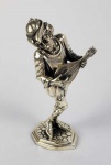 BUCCELLATI, MARIO (1891-1965)   MÚSICO MEDIEVAL -TOCADOR DE ALAÚDE  LINDA ESCULTURA EM PRATA DE LEI COM ASSINATURA DE MARIO BUCCELLATI E CONTRASTES. O PERSONAGEM É ASSENTE SOBRE BASE SIMULANDO PAVIMENTO EM PEDRA. INCRIVEL QUALIDADE ESCULTÓRICA!  COMPÕE O CONJUNTO DE QUATRO INSTRUMENTISTAS APREGOADOS NESSA SEQUENCIA.  ITÁLIA, PRIMEIRA METADE DO SEC. XX. 13 CMNOTA: A empresa italiana de Buccellati é famosa por jóias de ouro textural e requintados objetos de prata. As principais realizações do design da empresa Buccellati abrangem quatro décadas: das décadas de 1920 a 1960.As peças são ousadas e instantaneamente reconhecíveis, com um estilo que faz referência aos grandes ourives do Renascimento. O aspecto mais distintivo das peças de Buccellati é a rica qualidade textural, Mario Buccellati foi o primeiro a introduzir a técnica de gravação de textura. As técnicas de gravura mais conhecidas são o rigato (linhas paralelas cortadas na superfície do metal para obter um efeito de brilho), telato (textura, obtida por linhas cruzadas finas, que imita a superfície de linho), segreginato (gravura em todas as direções possíveis, sobreposição texturas), ornato (decoração, baseada em formas da natureza: animais, folhas, flores), modellato (a técnica de gravura mais delicada, que consiste em reproduzir vários desenhos esculpidos em três dimensões em escala minúscula, usados principalmente para a decoração das fronteiras ).As peças são criadas para olhar e sentir como seda, damasco, tule, renda ou linho. O uso de metais misturados (prata e ouro, platina e ouro) também é típico. Se pedras preciosas são usadas, geralmente são incomuns: grandes cabochões, esmeraldas esculpidas e rubis, diamantes de lapidação rosa. De acordo com a história da família, a primeira incursão da Buccellati no comércio de jóias foi em meados do século XVIII, quando Contardo Buccellati trabalhou como ourives em Milão. Em 1903, Mario Buccellati reviveu a tradição da família, aprendendo na prestigiosa Beltrami & Beltrami de Milão aos doze anos de idade. Em 1919, Buccellati assumiu a empresa, mudando seu nome para Buccellati. A aclamação internacional rapidamente se seguiu. Ao exibir-se na Exposição de 1920 em Madri, Mario Buccellati chamou a atenção do público quando lançou uma peça cara pela janela quando uma mulher pediu um desconto e gritou: Eu não sou um comerciante! No dia seguinte, centenas de pessoas compareceram a seu estande, curiosas para verem as peças do joalheiro desconhecido. Tudo vendido. Buccellati foi então convidado a expor seu trabalho em uma exposição individual; Aristocratas espanhóis vieram em massa, incluindo a família real que se tornou cliente ao longo da vida do artista. Nos anos que se seguiram, o trabalho de Buccellati ganhou seguidores leais na Itália e no exterior. O poeta Gabriele D'Annunzio apelidou-o de "O Príncipe dos Ourives" e encomendou peças às centenas. Em 1949, Mario Buccellati foi contratado para criar um ícone do Papa Pio XII para a Princesa Margaret para marcar a ocasião extraordinária da primeira visita de um membro da família real Britânica à Cidade do Vaticano em centenas de anos. Esta magnífica obra de arte pode ser admirada hoje no Museu de Arte de Chianciano na Toscana.  Quando seus cinco filhos atingiram a maioridade, todos, menos um, entraram no negócio: Frederico, Gianmaria, Luca e Lorenzo. Novas lojas foram abertas em Roma (1925) e Florença (1929).Em 1951, Buccellati tornou-se o primeiro designer de jóias italiano a estabelecer-se na Quinta Avenida, em Nova York. Em 1967, quando Mario Buccellati morreu, os irmãos dividiram o negócio.