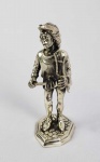 BUCCELLATI, MARIO (1891-1965)   MÚSICO MEDIEVAL -TOCADOR DE DIAPASÃO   LINDA ESCULTURA EM PRATA DE LEI COM ASSINATURA DE MARIO BUCCELLATI E CONTRASTES. O PERSONAGEM É ASSENTE SOBRE BASE SIMULANDO PAVIMENTO EM PEDRA. INCRIVEL QUALIDADE ESCULTÓRICA!  COMPÕE O CONJUNTO DE QUATRO INSTRUMENTISTAS APREGOADOS NESSA SEQUENCIA.  ITÁLIA, PRIMEIRA METADE DO SEC. XX. 13 CMNOTA: A empresa italiana de Buccellati é famosa por jóias de ouro textural e requintados objetos de prata. As principais realizações do design da empresa Buccellati abrangem quatro décadas: das décadas de 1920 a 1960.As peças são ousadas e instantaneamente reconhecíveis, com um estilo que faz referência aos grandes ourives do Renascimento. O aspecto mais distintivo das peças de Buccellati é a rica qualidade textural, Mario Buccellati foi o primeiro a introduzir a técnica de gravação de textura. As técnicas de gravura mais conhecidas são o rigato (linhas paralelas cortadas na superfície do metal para obter um efeito de brilho), telato (textura, obtida por linhas cruzadas finas, que imita a superfície de linho), segreginato (gravura em todas as direções possíveis, sobreposição texturas), ornato (decoração, baseada em formas da natureza: animais, folhas, flores), modellato (a técnica de gravura mais delicada, que consiste em reproduzir vários desenhos esculpidos em três dimensões em escala minúscula, usados principalmente para a decoração das fronteiras ).As peças são criadas para olhar e sentir como seda, damasco, tule, renda ou linho. O uso de metais misturados (prata e ouro, platina e ouro) também é típico. Se pedras preciosas são usadas, geralmente são incomuns: grandes cabochões, esmeraldas esculpidas e rubis, diamantes de lapidação rosa. De acordo com a história da família, a primeira incursão da Buccellati no comércio de jóias foi em meados do século XVIII, quando Contardo Buccellati trabalhou como ourives em Milão. Em 1903, Mario Buccellati reviveu a tradição da família, aprendendo na prestigiosa Beltrami & Beltrami de Milão aos doze anos de idade. Em 1919, Buccellati assumiu a empresa, mudando seu nome para Buccellati. A aclamação internacional rapidamente se seguiu. Ao exibir-se na Exposição de 1920 em Madri, Mario Buccellati chamou a atenção do público quando lançou uma peça cara pela janela quando uma mulher pediu um desconto e gritou: Eu não sou um comerciante! No dia seguinte, centenas de pessoas compareceram a seu estande, curiosas para verem as peças do joalheiro desconhecido. Tudo vendido. Buccellati foi então convidado a expor seu trabalho em uma exposição individual; Aristocratas espanhóis vieram em massa, incluindo a família real que se tornou cliente ao longo da vida do artista. Nos anos que se seguiram, o trabalho de Buccellati ganhou seguidores leais na Itália e no exterior. O poeta Gabriele D'Annunzio apelidou-o de "O Príncipe dos Ourives" e encomendou peças às centenas. Em 1949, Mario Buccellati foi contratado para criar um ícone do Papa Pio XII para a Princesa Margaret para marcar a ocasião extraordinária da primeira visita de um membro da família real Britânica à Cidade do Vaticano em centenas de anos. Esta magnífica obra de arte pode ser admirada hoje no Museu de Arte de Chianciano na Toscana.  Quando seus cinco filhos atingiram a maioridade, todos, menos um, entraram no negócio: Frederico, Gianmaria, Luca e Lorenzo. Novas lojas foram abertas em Roma (1925) e Florença (1929).Em 1951, Buccellati tornou-se o primeiro designer de jóias italiano a estabelecer-se na Quinta Avenida, em Nova York. Em 1967, quando Mario Buccellati morreu, os irmãos dividiram o negócio.