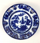 FLOW BLUE SHANGAI  LINDO PRATO EM FAIANÇA COM DECORAÇÃO COM PAGODES E CENAS LACUSTRES. MARCAS DA MANUFATURA SOB A BASE INGLATERRA, MEADOS DO SEC. XIX. 33 CM DE DIAMETRO.NOTA:A louça borrão foi produto de experiência dos fabricantes ingleses que na primeira metade do sec. XIX iniciaram tentativas para decorar a porcelana com cobalto, técnica milenar desenvolvida pelos chineses. Nas primeiras décadas a técnica, ainda não dominada totalmente, produzia louça com bela tonalidade azul cobalto, mas sem definição precisa da decoração. Daí o nome borrão. Como não tiveram boa aceitação nos mercados europeus eram enviadas como lastro nos navios para serem comercializadas nas colônias da América. Essa é a louça primitiva utilizada no Brasil pelas famílias abastadas e bastante colecionada nos dias atuais por sua raridade e beleza.