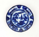 FLOW BLUE SHANGAI  LINDO PRATO EM FAIANÇA COM DECORAÇÃO COM PAGODES E CENAS LACUSTRES. MARCAS DA MANUFATURA SOB A BASE. TAMANHO MUITO RARO! INGLATERRA, MEADOS DO SEC. XIX. 15,5 CM DE DIAMETRO.NOTA:A louça borrão foi produto de experiência dos fabricantes ingleses que na primeira metade do sec. XIX iniciaram tentativas para decorar a porcelana com cobalto, técnica milenar desenvolvida pelos chineses. Nas primeiras décadas a técnica, ainda não dominada totalmente, produzia louça com bela tonalidade azul cobalto, mas sem definição precisa da decoração. Daí o nome borrão. Como não tiveram boa aceitação nos mercados europeus eram enviadas como lastro nos navios para serem comercializadas nas colônias da América. Essa é a louça primitiva utilizada no Brasil pelas famílias abastadas e bastante colecionada nos dias atuais por sua raridade e beleza.