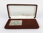 CENTENÁRIO DO ENGENHO CENTRAL QUISSAMÁ  MACAÉ  MEDALHA GRAVADA EM PRATA DE LEI 900 NO ANO DE 1977. VERSO PAINEL DE SAMI MATTAR REPRESENTANDO A ATIVIDADE AÇUICAREIRA E NO ANVERSO CASA DA FAZENDA QUISSAMÃ. NO ESTOJO ORIGINAL. 7,2 X 53 CM 118,6 GNOTA: Inicialmente, os engenhos eram movidos a tração humana, tração animal (trapiches) ou moinhos d´água. A produção artesanal gerava vários tipos de açúcar com qualidades variáveis, e a linha de produtos podia incluir também aguardente, melado e rapadura. Por volta de 1850, há uma grande concentração econômica com a implantação de engenhos com máquinas a vapor que são muito mais eficientes do que todos os outros. Os proprietários de terra desativaram seus engenhos e passaram a vender a cana-de-açúcar para o Cia Engenho Central de Quissamã que levantou um financiamento se para se instalar e adquirir os equipamentos mais modernos. Em 1865, em Quissamã, só há engenhos com máquinas a vapor cujos donos eram os grandes proprietários. Após 1850, a produção de açúcar do norte fluminense, mesmo com preços estáveis, cresceu em média 3,62% ao ano e atingiu o seu máximo (no século XIX) no ano de 1872. A capacidade produtiva dos engenhos com máquinas a vapor atingiu então seu limite máximo havendo necessidade de aumentar a produção com eficiência, o que só seria possível com a concentração e especialização em plantas produtivas maiores. A Revolução Industrial já tinha criado as soluções tecnológicas necessárias, seja com equipamentos maiores e mais eficientes, seja com o uso de ferrovias capazes de levar a cana-de-açúcar da plantação até a unidade de processamento e o açúcar produzido até o mercado consumidor. Existiam dois modelos de produção a serem adotados: o engenho central e a usina de açúcar. Um engenho central era uma planta industrial moderna que recebia cana-de-açúcar de diversos plantadores independentes e produzia açúcar e, às vezes, aguardente. Operava como uma cooperativa, mas com caráter semi-oficial, pois era obrigada a processar a cana de terceiros. Já uma usina processava a cana-de-açúcar de apenas um plantador, que podia escolher ou não processar a cana-de-açúcar de terceiros. O próprio governo imperial percebeu a importância da modernização da produção de açúcar e criou linhas de subsídio ao crédito para construção de engenhos centrais. Uma das formas de subsídio foi que o governo garantia que os juros dos empréstimos tomados para construção de engenhos centrais não fossem superiores a um determinado valor. A construção de usinas não recebeu subsídios ao crédito. Alguns requisitos para concessão do crédito inibiam, mas não proibiam, que os engenhos utilizassem mão-de-obra escrava.Diversos proprietários de engenhos, individualmente ou em grupos, passaram então a pensar em erguer usinas ou engenhos centrais. O projeto empresarial do Engenho Central de Quissamã foi baseado no famoso Relatório de Burton sobre os engenhos centrais da Martinica, documento traduzido e estudado por João José Carneiro da Silva, o barão de Monte Cedro. Este documento convenceu um grupo de pessoas que eram filhos, genros e netos do 1º Barão e Visconde de Araruama a fundar o primeiro Engenho Central de açúcar da América Latina e a desativar os engenhos obsoletos das fazendas. O Engenho Central de Quissamã foi inaugurado em 12 de Setembro de 1877 com a primeira moagem acompanhada pelo imperador Dom Pedro II e pela imperatriz Teresa Cristina. O primeiro presidente do Engenho Central de Quissamã foi Bento Carneiro da Silva, o futuro conde de Araruama, o qual foi sucedido por seu irmão Manuel Carneiro da Silva, visconde de Ururaí, que dirigiu a empresa por 26 anos. Os primeiros diretores foram o tenente-coronel João Caetano Carneiro da Silva (futuro barão e visconde de Quissamã), José Ribeiro de Castro Sobrinho e Francisco Pereira do Nascimento. Os primeiros fiscais (da administração) foram o comendador José Ribeiro de Castro e Manuel Antônio Ribeiro de Castro.  medida que o Brasil se industrializava, as usinas de açúcar do estado de São Paulo compravam equipamentos modernos das indústrias nascentes. Assim o estado de São Paulo superou o norte fluminense e depois tornou-se a região brasileira de maior produção de açúcar e álcool. O Engenho Central de Quissamã não recebeu investimentos significativos para modernização durante o século XX. Quando foi desativado, em 2003, ainda utilizava uma máquina a vapor do século XIX, uma raridade tecnológica, que era a mais antiga em operação no mundo. Também nunca houve preocupação com danos ao meio-ambiente, o que era comum entre os empresários da época. Durante mais de 100 anos, cargas poluidoras líquidas foram lançadas no canal Campos-Macaé e, portanto, levadas para a região do atual Parque Nacional da Restinga de Jurubatiba. Em 1967, o Instituto do Açúcar e do Álcool obrigou a desativação de usinas de açúcar com pouca capacidade de produção. Mais da metade das usinas então existentes são fechadas no estado do Rio de Janeiro. Apesar de ter mudado pouco desde a sua inauguração, o Engenho Central de Quissamã é um dos puderam permanecer em operação, mesmo assim não consegue acompanhar o ritmo de modernização do setor açucareiro. Seus últimos proprietários foram Joaquim Bento e Edilberto Ribeiro de Castro, descendentes de alguns dos sócios-fundadores. Em janeiro de 2003, o grupo Empresas JP, pertencente ao empresário pernambucano José Pessoa, arrendou 8 mil hectares de terra do Engenho Central de Quissamã para o plantio de cana. Entretanto, apesar de várias promessas de reabertura, a usina está fechada até hoje e já foi desmantelada.