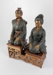 ESCOLA DE HANOI - PAR DE ESCULTURAS EM BRONZE REPRESENTANDO CASAL DE DIGNATÁRIOS. ASSENTES SOBRE BASE EM MADEIRA ELABORADAMENTE ESCULPIDA COM RESERVA CENTRAL EM PEDRA MARMÓREA. JAPÃO, PERÍODO EDO. 37 CM DE ALTURA (O PERSONAGEM MASCULINO), 30 CM DE ALTURA (O PERSONAGEM FEMININO). A BASE TEM 33 X 16 CM