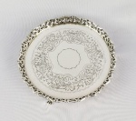 SALVA EM PRATA DE LEI COM GALERIA VAZADA. MARCAS DE CONTRASTE 833 E PRATEIRO SP.  PLANO DECORADO COM ROCAILLES. ASSENTE SOBRE TRÊS PÉS EM GARRA. BRASIL, MEADOS DO SEC. XX. 19 CM DE DIAMETRO. 330 G