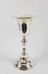 LINDO CÁLICE EM PRATA DE LEI BATIDA COM INTERIOR EM VERMEIL ACOMPANHADO DE SUA PATENA. MARCAS DE CONTRASTES DOS PAÍSES BAIXOS. DE INSPIRAÇÃO ART DECO AS LINHAS SOBRIAS E ELEGANTES REMATADAS PELA TEXTURA DA PRATA BATIDA SÃO VALORIZADAS PELO EMBLEMA RELEVADO COM UM PEIXE, UMA CESTA DE PÃES E UMA CRUZ LATINA QUE ALÉM  DA SIMBOLOGIA CRISTÃ E DA EUCARISTIA APONTAM PARA O MILAGRE MULTIPLICAÇÃO DOS PÃES  E PEIXES OPERADO POR CRISTO. PAÍSES BAIXOS, 17 CM DE ALTURA. 680 GNOTA: O MILAGRE DA MULTIPLICAÇÃO DOS PÃES. S. MATHEUS 14: 13-21 13 Ouvindo o que havia ocorrido, Jesus retirou-se de barco, em particular, para um lugar deserto. As multidões, ao ouvirem falar disso, saíram das cidades e o seguiram a pé. 14 Quando Jesus saiu do barco e viu tão grande multidão, teve compaixão deles e curou os seus doentes. 15 Ao cair da tarde, os discípulos aproximaram-se dele e disseram: Este é um lugar deserto, e já está ficando tarde. Manda embora a multidão para que possam ir aos povoados comprar comida. 16 Respondeu Jesus: Eles não precisam ir. Dêem-lhes vocês algo para comer. 17 Eles lhe disseram: Tudo o que temos aqui são cinco pães e dois peixes. 18 Tragam-nos aqui para mim, disse ele. 19 E ordenou que a multidão se assentasse na grama. Tomando os cinco pães e os dois peixes e, olhando para o céu, deu graças e partiu os pães. Em seguida, deu-os aos discípulos, e estes à multidão. 20 Todos comeram e ficaram satisfeitos, e os discípulos recolheram doze cestos cheios de pedaços que sobraram. 21 Os que comeram foram cerca de cinco mil homens, sem contar mulheres e crianças.