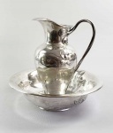 L. POSEN  SOBERBO GOMIL E SUA LAVANDA EM PRATA DE LEI ESTILO E ÉPOCA ART NOUVEAU. MARCAS DE CONTRASTE LUA E COROA, TEOR 800 E PRATEIRO DA MANUFATURA DA VIUVA DE LÁZARO POSEN. A DECORAÇÃO É MAGNÍFICA! ELEMENTOS RELEVADOS DE UM AMBIENTE AQUÁTICO COM RIO CONTENDO LINDOS PEIXES E PLANTAS AQUÁTICAS QUE SE ELEVAM SOBRE A ÁGUA COM FLORES E RAMAGENS. TAMBÉM UMA LIBÉLULA VOANDO. A ELEGANTE ALÇA DO GOMIL TEM FEITIO DE HASTES FLORAIS E EXUBERANTES FLORES QUE UNEM A ALÇA AO CORPO DO GOMIL. MUITAS VEZES OUVI O MESMO COMENTÁRIO SOBRE O PORQUE DE NÃO EXISTIREM PEÇAS COM A BELEZA DAS PRODUZIDAS PELA MANUFATURA WMF EM PRATA DE LEI. ESSE GOMIL DESMISTIFICA ESSA QUESTÃO, PRATA DE LEI ALEMÃ COM A QUALIDADE E BELEZA DECORATIVA DAS MAIS BELAS PEÇAS WMF. ALEMANHA, FINAL DO SEC. XIX. 38 X 38 CM. 2875 GNOTA: A empresa foi fundada em Frankfurt em 1869 por Brendina Wetzlar, viúva de Lázaro Jacob Posen, ourives e varejista de descendência polonesa. Sob a administração da viúva Posen, a empresa se tornou o maior fornecedor de prata Judaica no final do século XIX. Seu filho Jacob L. Posen ingressou na empresa em 1880 e, em 1900, a grande equipe de ourives e gravadores da empresa produzia algumas das melhores pratas do país. Eles receberam um mandado real em 1903. No século 20, a empresa estava sob a direção dos netos de Brendina, Jakob, Hermann e Moritz Posen. Em 1938, a empresa foi fechada e saqueada à força na Kristallnacht (Noite dos Cristais). NOITE DOS CIRSTAIS: Na noite de 9 de novembro de 1938 teve início a onda de violência contra os judeus em todo o Reich. Embora os ataques parecessem expontâneos, como se fossem uma revolta natural da população alemã contra o assassinato de um oficial daquele país por um adolescente judeu em Paris, na verdade, o ministro alemão da propaganda, Joseph Goebbels, e outros líderes nazistas haviam organizado os pogroms chacina dos judeus cuidadosamente, muito antes deles acontecerem. Num período de apenas dois dias, mais de 250 sinagogas foram queimadas, cerca de 7.000 estabelecimentos comerciais judaicos destruídos, dezenas de judeus foram mortos, e cemitérios, hospitais, escolas e casas judias saqueados, tudo ante a total indiferença da polícia e dos bombeiros e da população. Os pogroms ficaram conhecidos como Kristallnacht ou "Noite dos Cristais" também Noite dos Vidros Quebrados, devido aos vidros estilhaçados nas vitrines das lojas, sinagogas e moradias de judeus. Na manhã seguinte, 30.000 judeus alemães do sexo masculino foram presos pelo crime de serem judeus, e enviados a campos de concentração onde centenas acabaram morrendo. Algumas mulheres judias também foram detidas e enviadas para prisões locais. Estabelecimentos comerciais de propriedade de judeus não puderam ser reabertos, exceto os que passaram a ser gerenciados por não-judeus. Toques de recolher foram impostos, limitando as horas do dia em que os judeus podiam sair de suas casas. Após a Noite dos Cristais, a vida de adolescentes e crianças judias na Alemanha e na Áustria se tornou ainda mais difícil: além de serem barrados em museus, parques e piscinas, também foram expulsos das escolas públicas. Os jovens, assim como seus pais, passaram a viver totalmente segregados naqueles países. Desesperados, muitos judeus cometeram suicídio. As famílias judias desesperadamente passaram a tentar sair da Alemanha e da Áustria.