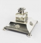 MAGNÍFICO TINTEIRO DE APARATO COM GUARNIÇÃO EM PRATA DE LEI. MARCAS DE CONTRASTE   JAVALI. BASE EM PLATEAU DECORADO COM PORTENTOSAS CABEÇAS DE LEÃO. TINTEIRO EM CRISTAL COM GUARNIÇÃO EM PRATA  DE LEI.  ASSENTE SOBRE QUATRO PÉS EM BOLA.  21 X 21 CM