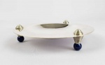 PUIFORCAT, JEAN  LINDO BOWL EM METAL ESPESSURADO A PRATA APOIADO POR PÉS COM FEITIO DE ESFERAS AZUIS SIMULANDO LAPIZ LAZULI EM ESMALTE E VERNIZ. DESIGN DO MAIS FAMOSO OURIVES DO PERIODO ART DECO FRANCES, JEAN PUIFORC. MUITO BOM ESTADO DE CONSERVAÇÃO.  FRANÇA, MEADOS DO SEC. XX. 19 CM DE DIAMETRONOTA: Este exemplo particular marcado foiproduzido por Jean Puiforcat (1897 - 1945), neto de Emile Puiforcat, que continuou a usar as iniciais de seu avô. Jean Puiforcat foi um famoso ourives, escultor e designer francês e é geralmente considerado o mais importante de todos os ourives franceses Art Déco. Suas obras são altamente valorizadas, notavelmente com Andy Warhol por ter sido um ávido colecionador de suas peças, muitas vezes adquirindo-as durante suas visitas a Paris nos anos 1970. Depois que Warhol morreu em 1987, a Sotheby's vendeu a coleção Puiforcat como parte da venda de memorabilia de Warhol em 1988. Um destaque foi uma terrina Puiforcat com decoração em  aventurina vendida por US $ 55.000. Atualmente, as obras de Puiforcat estão expostas no Victoria & Albert Museum e no Cooper Hewitt Smithsonian Design Museum em Manhattan.