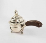 ELEGANTE PERFUMADOR EM PRATA DE LEI OITOCENTISTA. BELO FORMATO COM EXCELENTE QUALIDADE DE EXECUÇÃO! ASSENTE SOBRE TRES PÉS COM FEITIO DE GARRAS. A TAMPA RETICULADA TEM CAPRICHADAS FENESTRAS PARA DISSIPAR A FUMAÇA EM DOIS NÍVEIS. PROXIMO A PEGA AS FENESTRAS SEGUEM PADRÃO DE LAUREU E NA BORDA AS FENESTRAS ASSUMEM COMPOSIÇÃO GEOMÉTRICA. CABO COM PEGA EM MADEIRA. BRASIL, SEC. XIX. 26 CM DE COMPRIMENTO. 580 GNOTA: PERFUMADORES são uma herança ancestral ibérica que remonta a tradição dos mouros. Eram muito utilizados nas residências da América espanhola e portuguesa. As diversas flagrâncias queimadas perfumavam as salas e evitavam na concepção geral a entrada de doenças na casa (o mau cheiro era tido como fonte de doença).