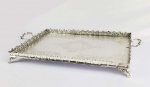 GRANDE TABULEIRO EM METAL ESPESSURADO A PRATA. GALERIA FENESTRADA. PLANO COM GUILLOCHES. ALÇAS LATERAIIS. ASSENTE SOBRE QUATRO PÉS. UM EXCELENTE BAR, APARENCIA DE PRATA DE LEI. ESTA EM OTIMO ESTADO. BRASIL, SEC. XX. 69 CM DE COMPRIMENTO.