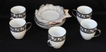 Conjunto com 5 xicaras e pires de porcelana importada na cor branca com as bordas decorada com desenhos geométricos em prata - suporte pintado com prata.