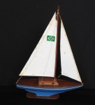 COLECIONISMO - Antigo barco a vela com a bandeira do Brasil, vela elaborada com material emborrachado, no estado, apresenta restauro, barco em madeira nobre com pigmentação em azul. Med. 20cm x 28cm.