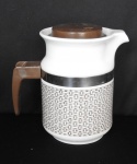 PORCELANA, Bule com ornamentação entrelaçado, na tonalidade marrom,  sobre fundo branco, detalhes em polímero, alça presa por fita de aço, manufatura POZZANI (Jundiaí, SP, fundada em 1934 por Francisco Pozzani; em 2002 foi vendida para um grupo de investidores com 80% de capital nacional e 20% de capital italiano, ainda em funcionamento), medindo 17 cm altura.