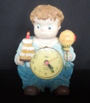 Relógio de resina com figura de jovem segurando bolo e bola festiva. Alt. 14cm
