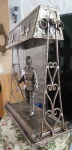 Deslumbrante luminária em metal, representando cavaleiro e sua armadura medieval, empunhando sua espada. Detalhes e adornos em toda a peça, como elmo articulaval e também calha que acondiciona os bocais. Nota-se na parte traseira da calha falta de três aplique em formato lírio de Capri. Carece refazer parte elétrica  (fios). Mede 47x41cm e base 41x19cm.