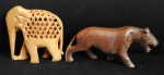 Lote com 2 (duas) esculturas de madeira  nobre, sendo um elefante indiano de madeira clara com decoração vazada apresentando um filhote em seu interior. Med. 10cm 10cm e um tigre em madeira escura med. 15cm x 7cm