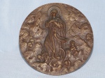 Placa redonda em bronze moldada com figura em alto relevo de Nossa Senhora da Conceição. Acompanha suporte de mesa posterior. Alt. 14cm.