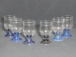 Seis taças para água em vidro translúcido com base em azul. Uma com base preta. Alt. 12cm.