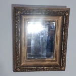 Espelho acondicionado em moldura de madeira decorada com flores em relevo e pintada de dourado. Med. total 18 x 37cm. Moldura com lascas próximo ao espelho.