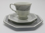 PORCELANA - Conjunto de xícara de chá, pires e prato para bolo em porcelana branca com frisos prateado e faixa preta. Med. 7,5 cm, 15 cm e 20 cm. Bicados