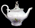 PORCELANA - Parte de jogo de chá em porcelana branca, nacional, decorada com relevo floral e frisos dourados. Composta de:  Bule de chá. Alt. 18 cm. Bicado na parte interna da borda.