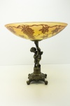 RAVAGNANI - Belíssima Fruteira com base em bronze cinzelado com querubim, pés garra e prato em pasta de vidro artístico assinado Ravagnani, com decoração de folhas e cachos de uva. Med. 29x30 cm.