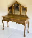 MOBILIÁRIO - Penteadeira estilo Inglês em madeira nobre com puxadores de bronze trabalhados, espelho bisotado com moldura finamente trabalhada em entalhe  e pés estilo chippendale. Possui 3 gavetas centrais. Med. 158x138x44 cm.
