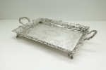 PRATA DE LEI - Graciosa bandeja retangular em prata de lei. Borda com galeria guilhochada e vazada em arcos e cervos. Pés quadripóides. Med. 9x47x28 cm e peso 1569 gr.