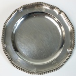 Prato em prata de lei batida, fundida, cinzelada e contrastada. Inglaterra, período Georgiano, Séc. XVIII. 540 gr. 25 cm de diâmetro.