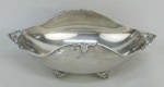 Petisqueira ovalada, em metal espessurado a prata, marca da manufatura Sheffield, com alças e pés vazados. Med. 8,5x23x10 cm.