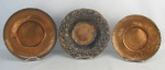 Três peças em cobre, sendo dois medalhões martelados e centro de mesa decorado com flores e folhas em relevo. Diams. medalhões 28,5x26 cm. Med. centro 4,5x28 cm.