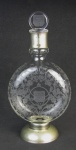 Baccarat - Garrafa em cristal francês, com marca da cristallerie na base, confeccionada para J. et. F. Martell Cognac. Decorada com lapidações de folhagens, arabescos e brasão em satiné. Guarnições em metal prateado. Parte interna do gargalo com trincado, sendo este encoberto pela guarnição em metal. Alt. 28 cm.