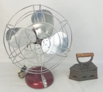 a) Ventilador em metal no tom vermelho, com hélice em metal prateado. Funcionando. Botão para regulagem de velocidade quebrado. Med. 54x44x28cm. b) Antigo ferro de passar a carvão, com alça em madeira. Marcas causadas pelo tempo. Med. 18x20,5x9cm.