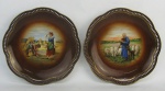 Par de pratos em porcelana alemã, com marca da manufatura Bavaria Schumann, tendo um decoração de cena com pastor e ovelhas e o outro colheita de trigo em policromia. Abas trabalhadas com vazados. Detalhes em dourado. Diams. 26,5 cm.