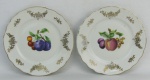 Par de pratos em porcelana italiana, com marca da manufatura Richard Finori, decorados com frutas em policromia e detalhes em dourado, tendo estes pequenos desgastes. Diams. 16,5 cm.