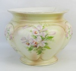 Cachepot em porcelana inglesa, com marca da manufatura Wedg Wood na base, decorado com flores e folhagens em policromia. Detalhes em dourado. Marcas de uso e aba com pequeno fio de cabelo. Med. 20,5x27,5cm.