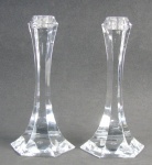 Par de castiçais em cristal francês, com marca da Cristallerie St. Louis na base, decorados com lapidações facetadas. Um apresenta dois lascados na base. Alt. 23cm.